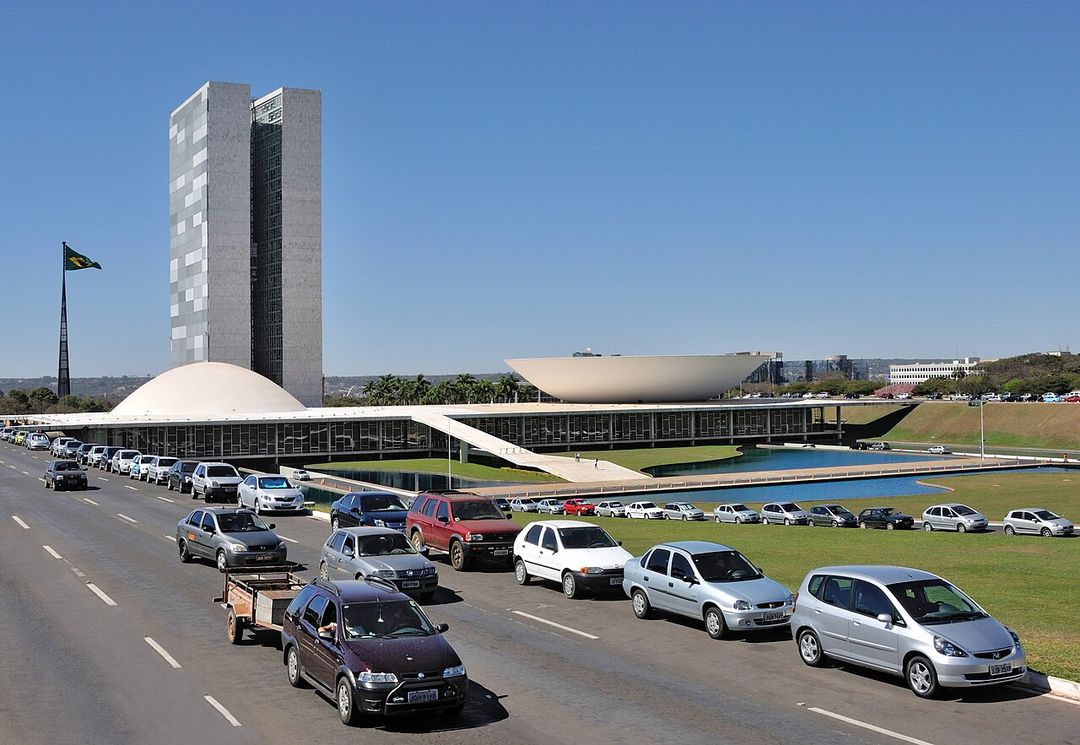 The twin white towers and saucer-shaped chambers of Brazil's National Congress building rising above the lawns of the Praca dos Tres Poderes in Brasilia