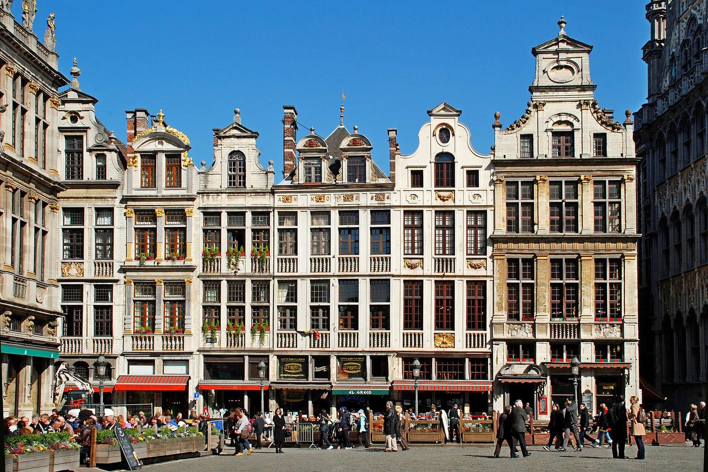 The ornate gilded facades of the guildhalls on the Grand-Place in Brussels, with the Gothic spire of the Town Hall rising behind