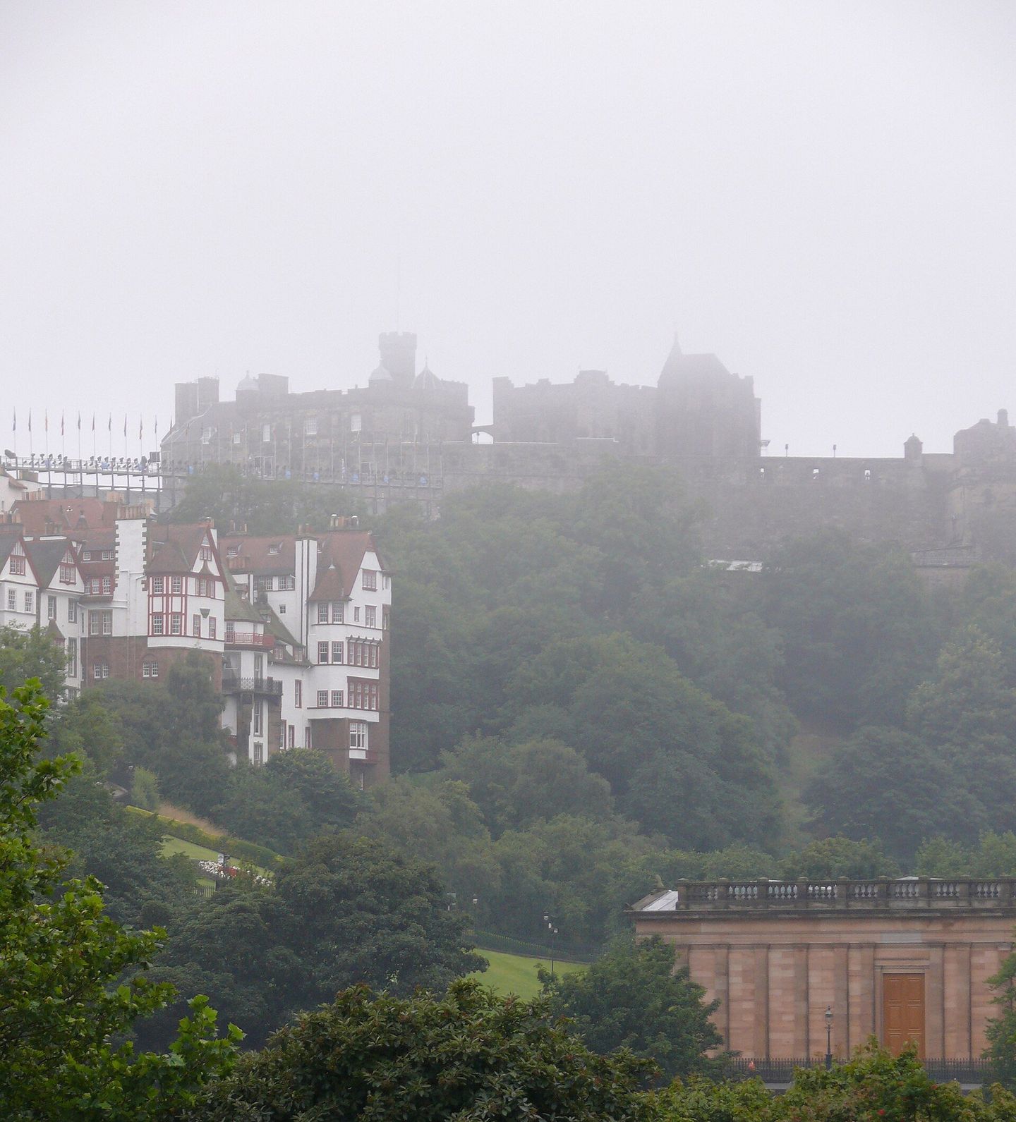 Edinburgh Castle rising above the city on its volcanic rock, seen through early morning haar from Princes Street