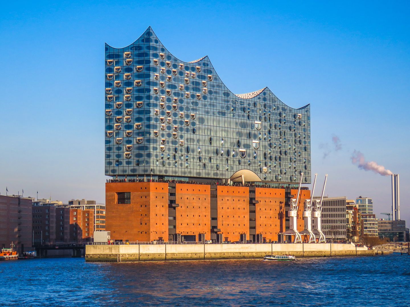 The wave-shaped glass crown of the Elbphilharmonie concert hall rising above the red-brick Speicherstadt warehouses and the harbour in Hamburg
